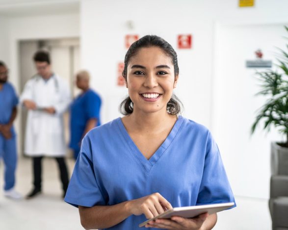 A smiling nurse holds a tablet.