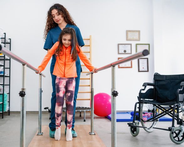 Nurse helps a girl to walk using support rails.