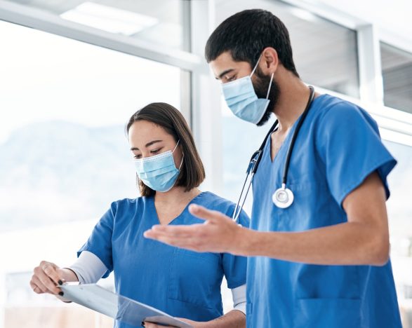 A female and male nurse look at a chart together.