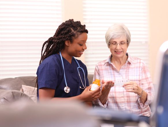 A female nurse helps a female patient with her medication.